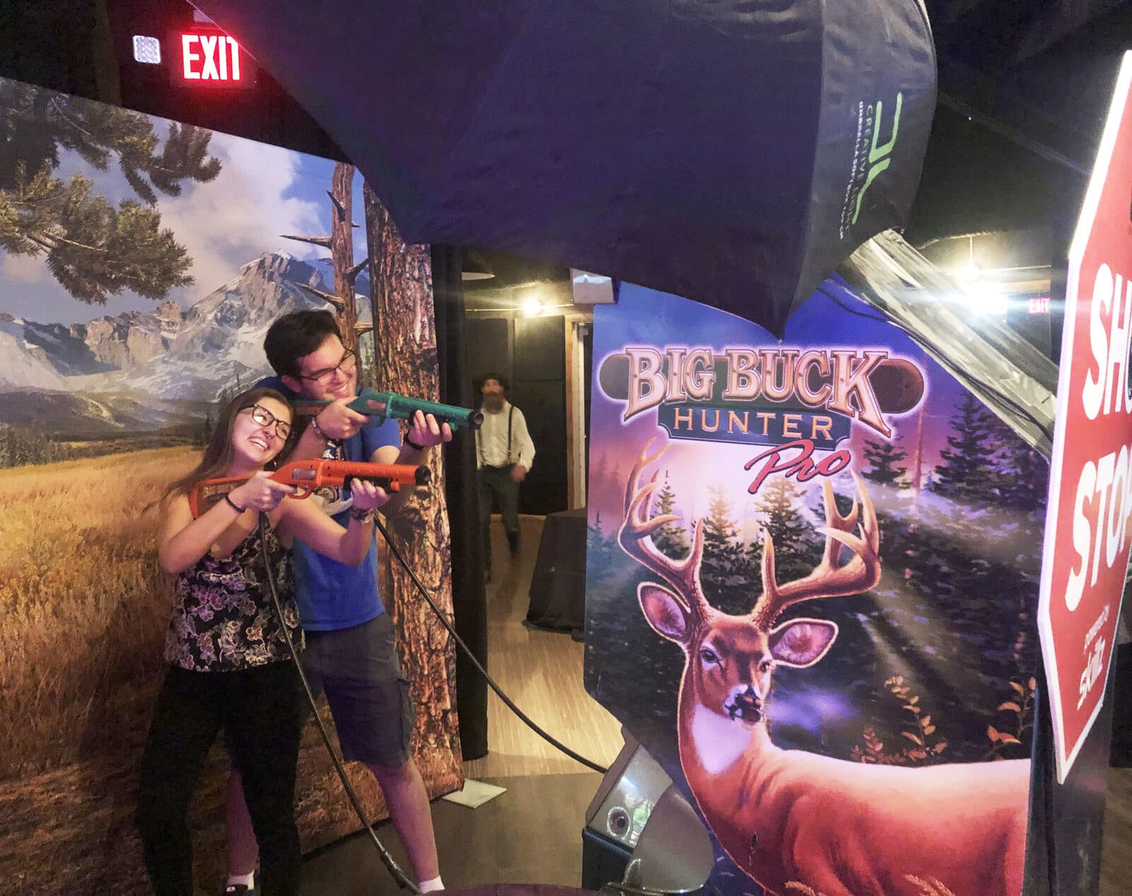 Players with light-gun controllers in front of the Big Buck Hunter set.